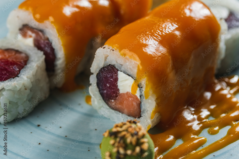 Sushi and soy sauce in a bowl and wooden chopsticks on a gray wo Sushi and soy sauce in a bowl and wooden chopsticks on a gray wo