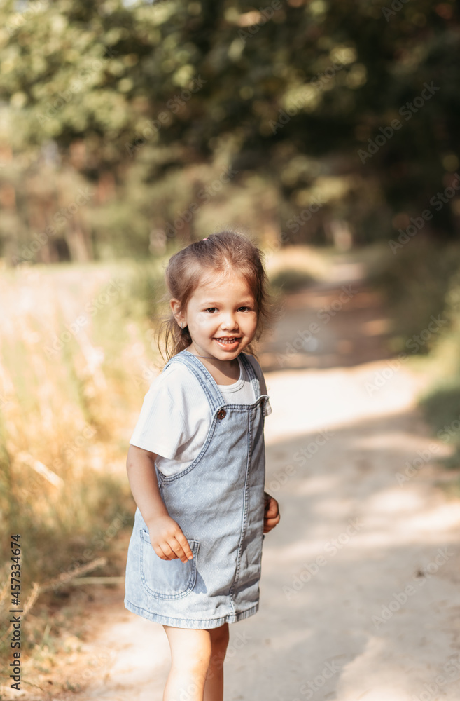 Positive charming little girl enjoying summer sunny day, expression emotions, having fun, happy child walking in summer day Positive charming little girl enjoying summer sunny day, expression emotions, having fun, happy child walking in summer day