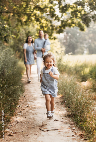 Young happy family with two children in nature in the summer walk. Healthy Smiling Dad, Mom and kids together