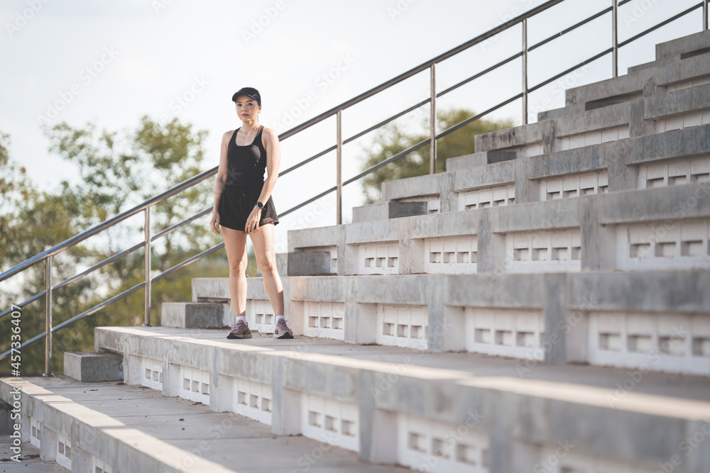A healthy adult Asian woman running up on concrete stairs of the city stadium to strengthen body