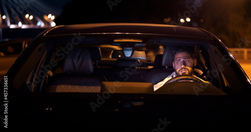Upset young man sitting in car on parking lot