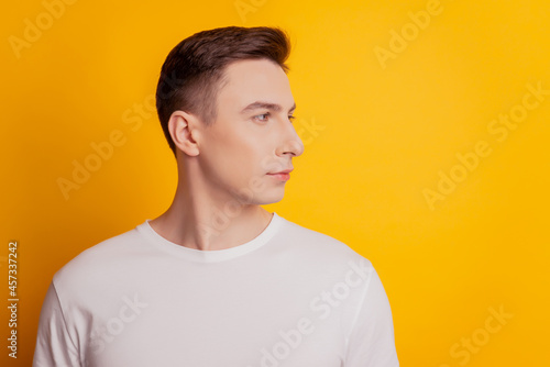 Portrait of masculine charming guy look side empty space on yellow background