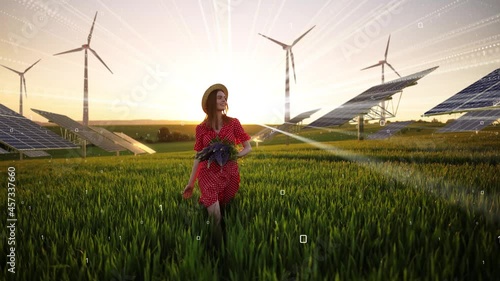 Young beautiful woman in hat holding a bouquet of flowers in summer field with Solar Panels Farm. Concept of Sustainability of planet. Green energy. Warm sunset colors. Wind Turbines Energy Production
