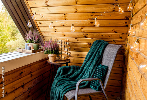 Fotobehang Small natural color wooden cabin balcony with heather flowers, candlelight flame, soft dark green plaid waiting on garden furniture chair