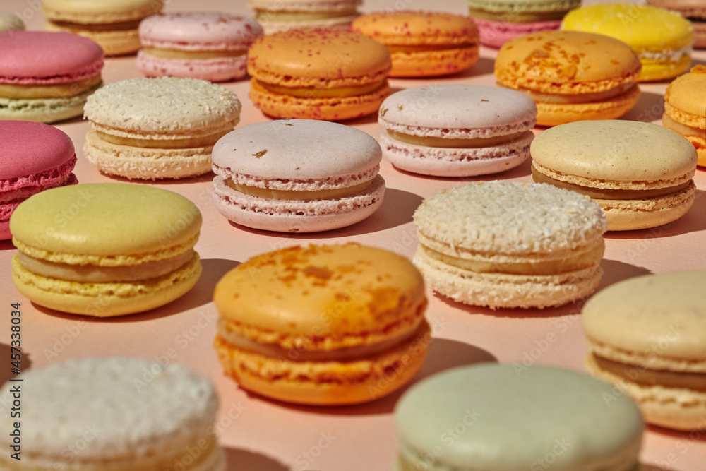 Colorful French macarons on light pink surface