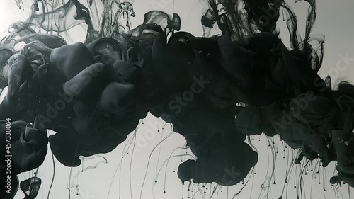 Abstract background. Slow motion of liquid black ink. Drops of black ink in water. Environmental pollution concept. Black cloud of ink on white background. Screensaver, relaxing meditative background