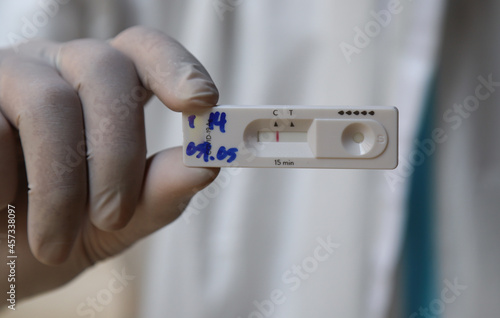 Closeup of hand with glove holding rapid antigen test kit for early Covid-19 detection. photo