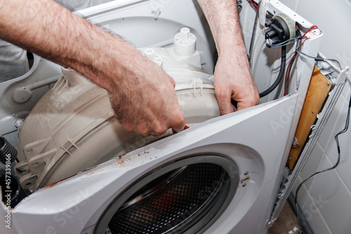 Handyman repairing a washing machine. The hands of man repair a washing machine.