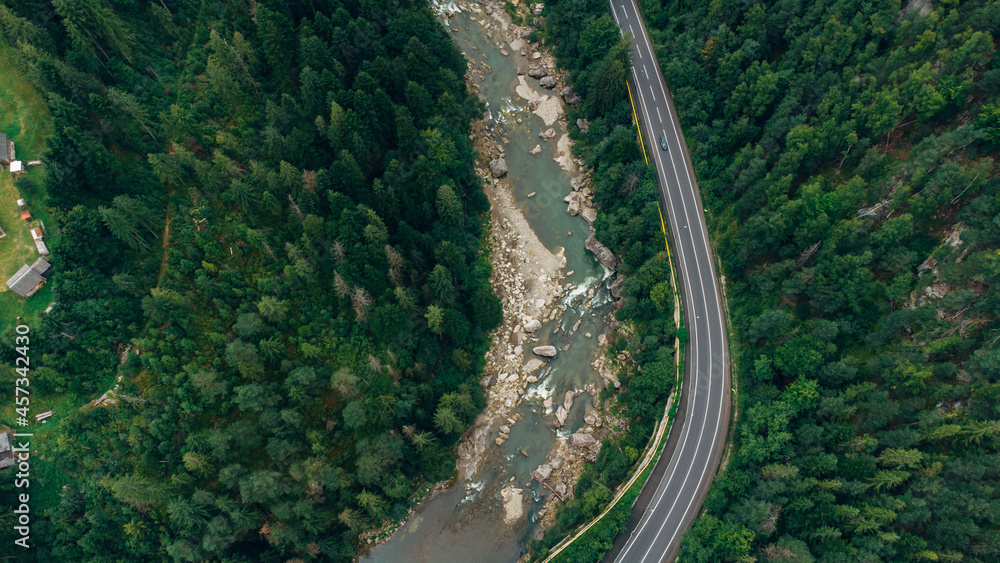 Fototapeta premium Beautiful aerial view of the road with mountains and forest, road and river, shot from above, carpathians, Ukraine