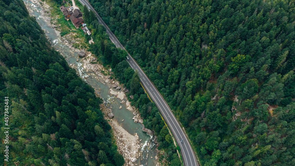 Fototapeta premium Beautiful aerial view of the road with mountains and forest, road and river, shot from above, carpathians, Ukraine