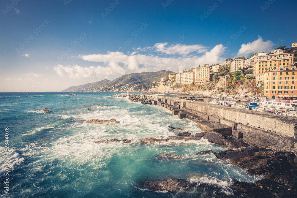 Fototapeta premium Sea and lighthouse in Camogli, Liguria region in Italy. Waves on the pier of the fabulous Italian scenery. Mediterranean Sea.