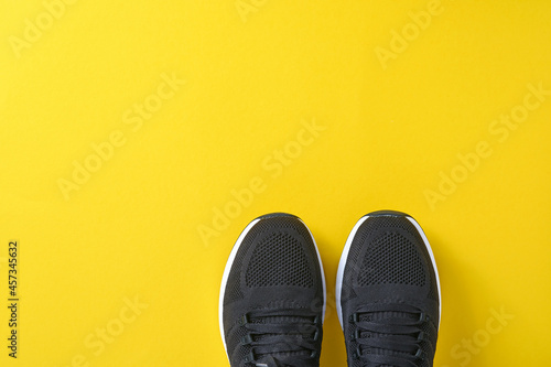 Black men sneakers on yellow background. Fashion blog or magazine concept. Men shoes, trendy sneakers, fashion, lifestyle. Mock up. Flat top view copy space minimal background.