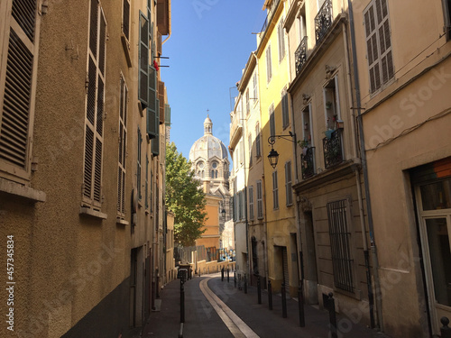 Pastel coloured residential buildings on a calm and friendly street with the Marseille Cathedral (Cathédrale de la Major) in the background, in Le Panier - Marseille's oldest neighborhood.