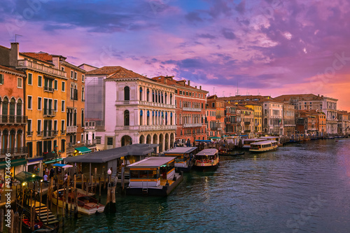 Sunset view of Grand Canal  Venice  Italy. Vaporetto or waterbus station  boats  gondolas moored by walkways  beautiful sunset clouds  UNESCO heritage