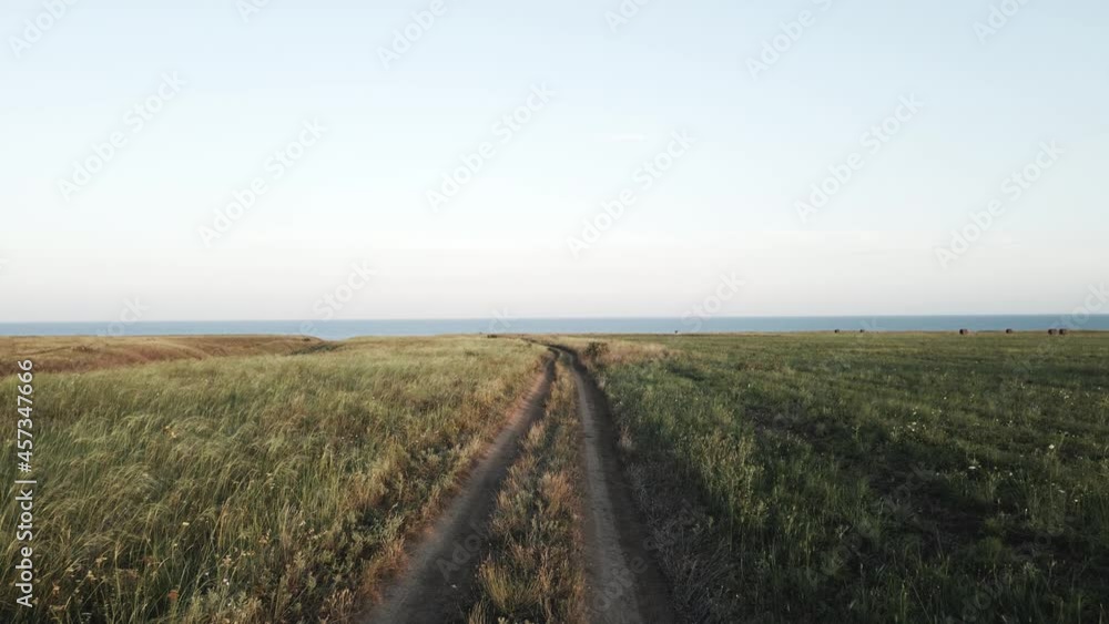 dirt road at sunset in a field by the sea dirt road at sunset in a field by the sea