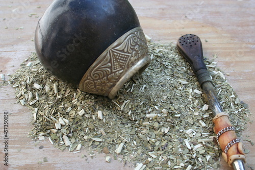 Infusión de yerba mate argentina y latinoamericana, con su mate o porongo y su bombilla con fondo de mesa de madera de pino desenfocado. photo