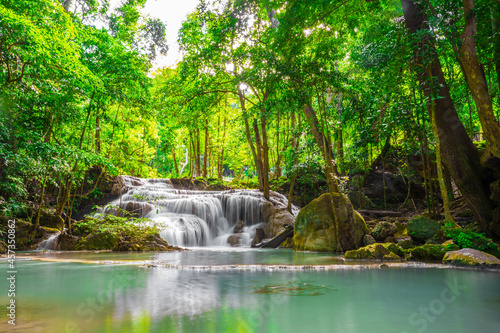 Waterfalls and fish swim in the emerald blue water in Erawan National Park. Erawan Waterfall is a beautiful natural rock waterfall in Kanchanaburi, Thailand.Onsen atmosphere. soft focus. © Pongvit
