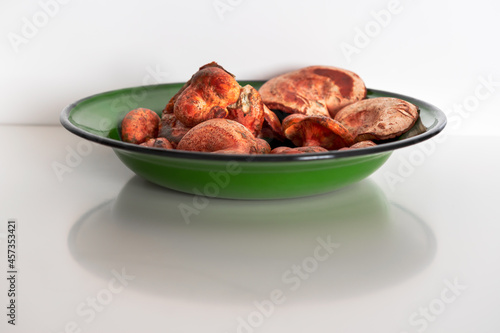 .red pine mushrooms in a green bowl on a white background photo