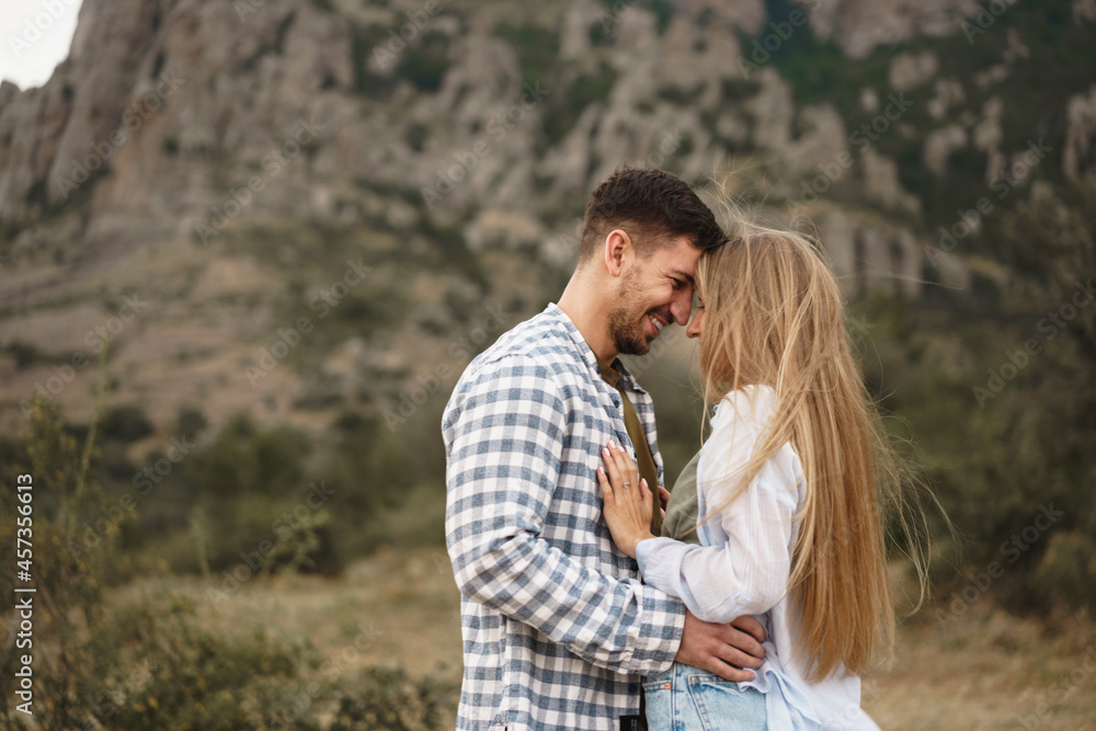 Happy loving couple hiking and hugging in mountains