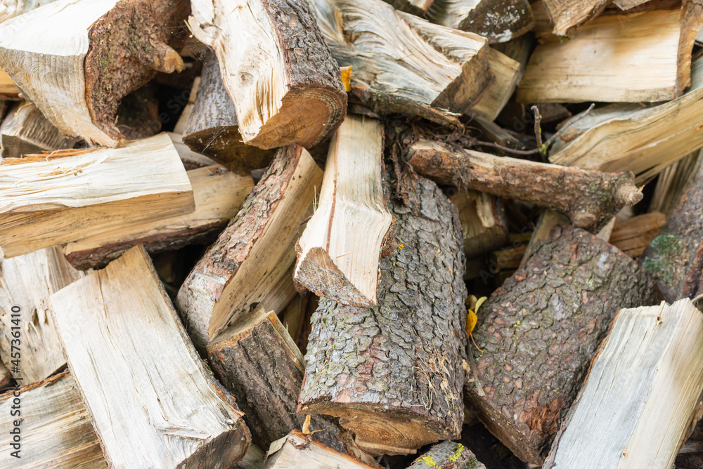 Fuel and heat source for the winter season.Preparing for the firewood heating season. Chopped firewood of different trees,outdoors. Fuel and heat source for the winter season.Preparing for the firewood heating season. Chopped firewood of different trees,outdoors.