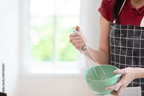 close up woman blogger making a bread, whisking something in a bowl and recording stream live video online from camera photo