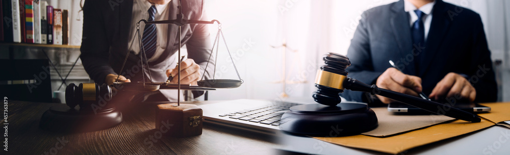 Justice and law concept.Male judge in a courtroom with the gavel, working with, computer and docking keyboard, eyeglasses, on table in morning light Justice and law concept.Male judge in a courtroom with the gavel, working with, computer and docking keyboard, eyeglasses, on table in morning light