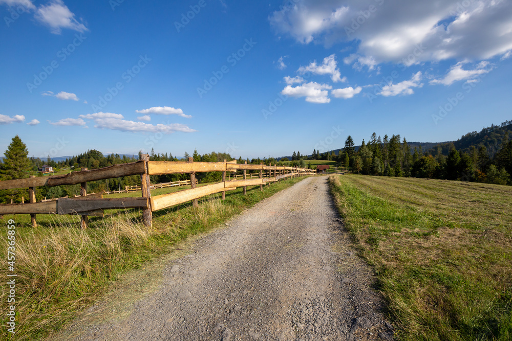 Dirt road in the Silesian Beskids, mountain landscape with path along wooden fence