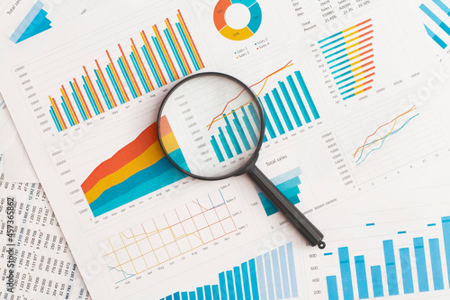 Business graphs, charts and magnifying glass on table. Financial development, Banking Account, Statistics photo