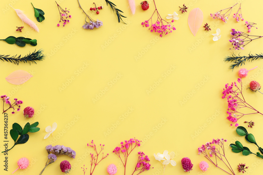 Fototapeta premium Top view image of pink, purple and green flowers composition over pastel yellow background .Flat lay