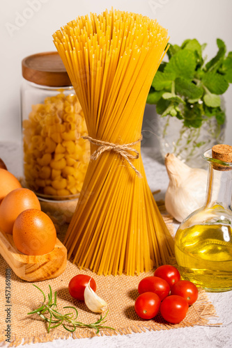 Carbo-diet - spaghetti, ditalini pasta together with a jar of olive oil, cherri tomatoes, garlic and eggs in eco-wooden palette.