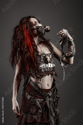 Attractive young woman with red eyes wearing post apocalyptic clothing and a gas mask © Warpedgalerie