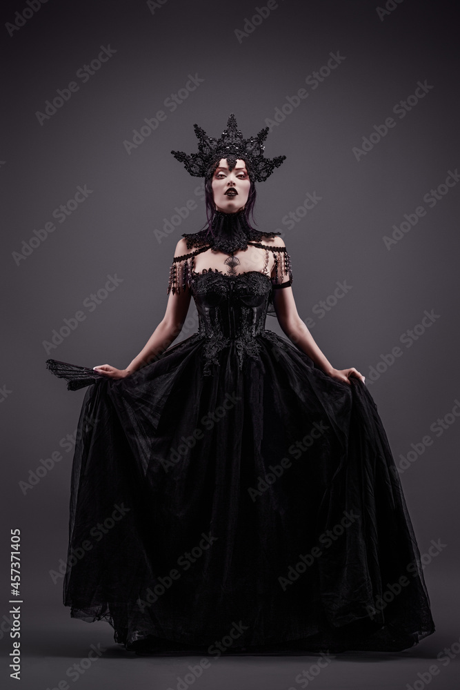 Attractive young woman wearing a black dress, a crown and a fan