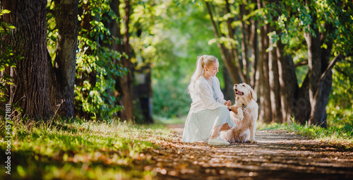 Concept banner Friendship girl and golden retriever. Pretty young woman with dog on background summer park