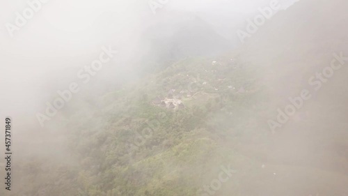 Drone footage of Traditional houses in Wae Rebo village in the jungle emerging from the fog. Famous Manggarai's traditional villages in Flores, Indonesia.  photo