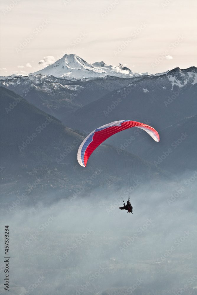Silhouetted Paraglider sails through the air near Mount Baker. Silhouetted Paraglider sails through the air near Mount Baker.
