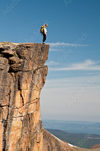 Active and fit female backpacker standing on the edge of a cliff