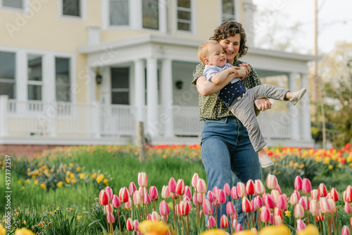 Mother playing with toddler son in backyard tulip garden in spri photo