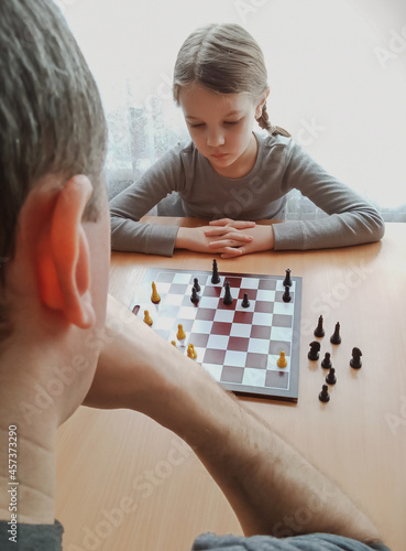 girl is playing chess at the table at home