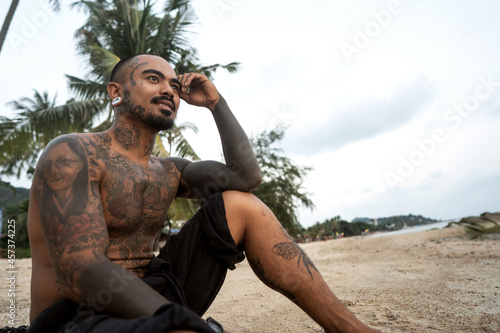 Thai guy on the seashore among the palm trees all in tattoos photo