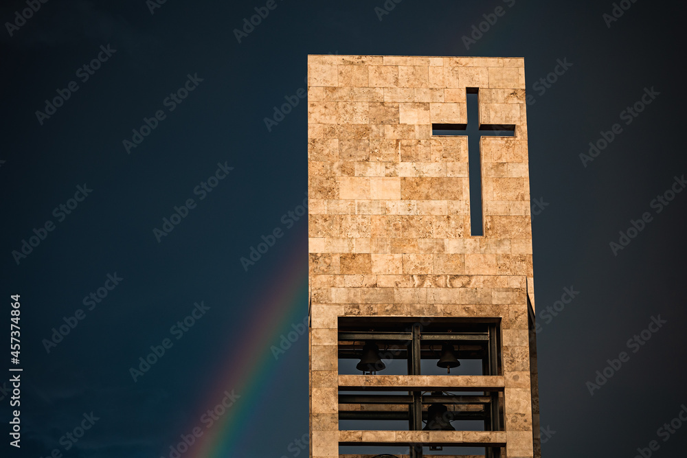 A rainbow above a modern church tower with christian cross