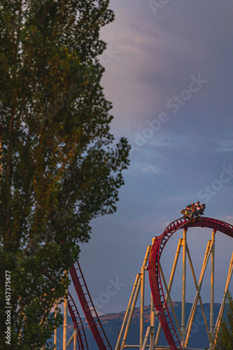 The train with some people is riding on roller coaster during the sunset © danieleorsi