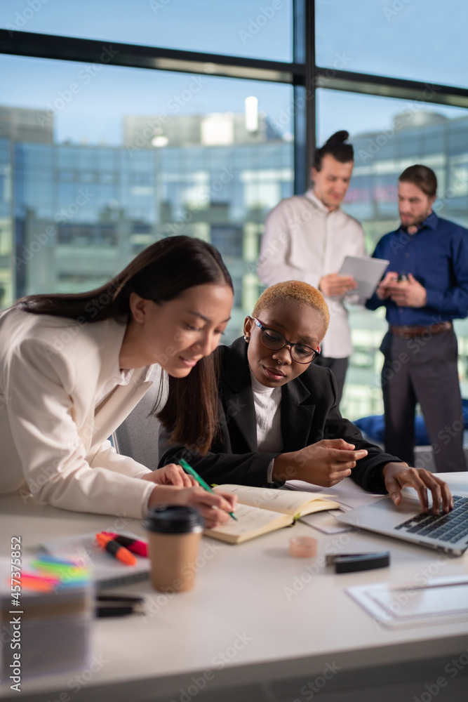 Multiracial colleagues making notes together Multiracial colleagues making notes together