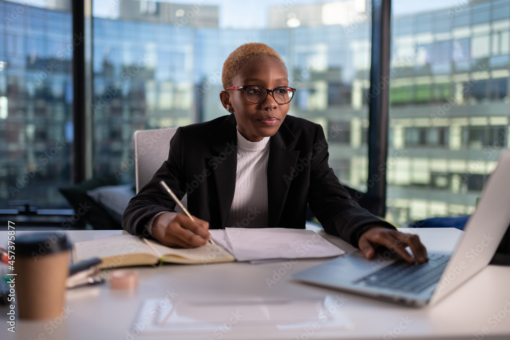 Black businesswoman writing down data Black businesswoman writing down data