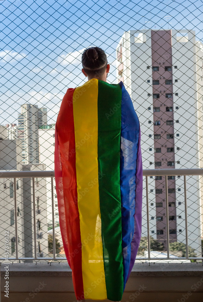 Gay man holding the rainbow flag symbol of gay pride on a balcon Stock ...