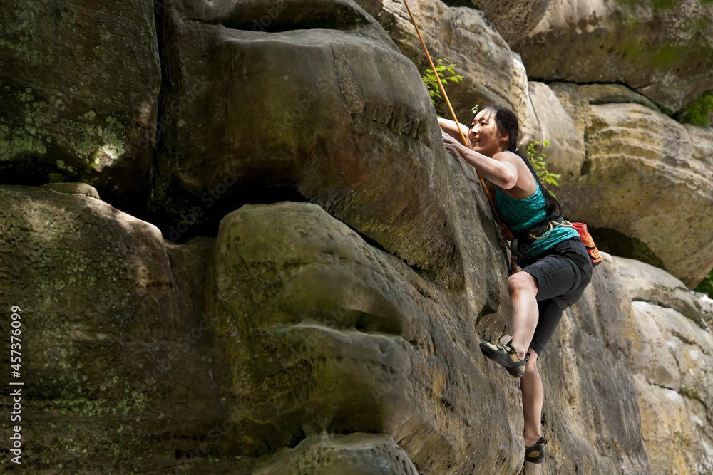 Woman climbing on the sandstone rocks at Harrison's Rock in England Woman climbing on the sandstone rocks at Harrison's Rock in England