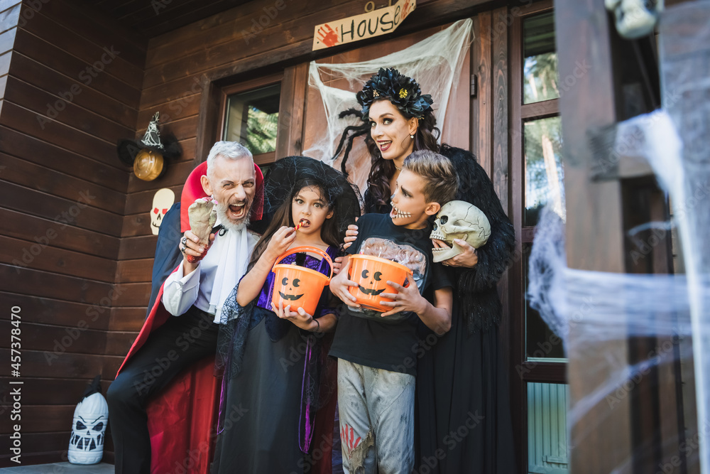 man holding toy hand and grimacing near family in halloween costumes