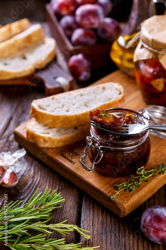 sun-dried plums on bread with garlic and provencal herbs on a wooden background