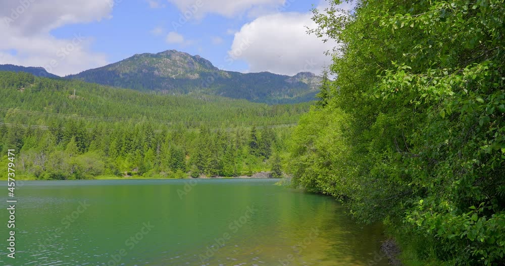 Establishing shot of lake with white clouds in Vancouver, Canada, North America. Day time on July 2021. Still camera view. ProRes 422 HQ. Establishing shot of lake with white clouds in Vancouver, Canada, North America. Day time on July 2021. Still camera view. ProRes 422 HQ.