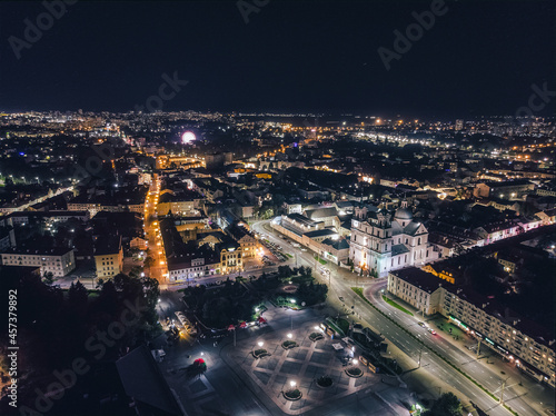 Aerial view of the night Grodno-a city in the west of Belarus. The central square with the Catholic Church. Panorama of the city with glowing streets and buildings. Drone aerial shot.