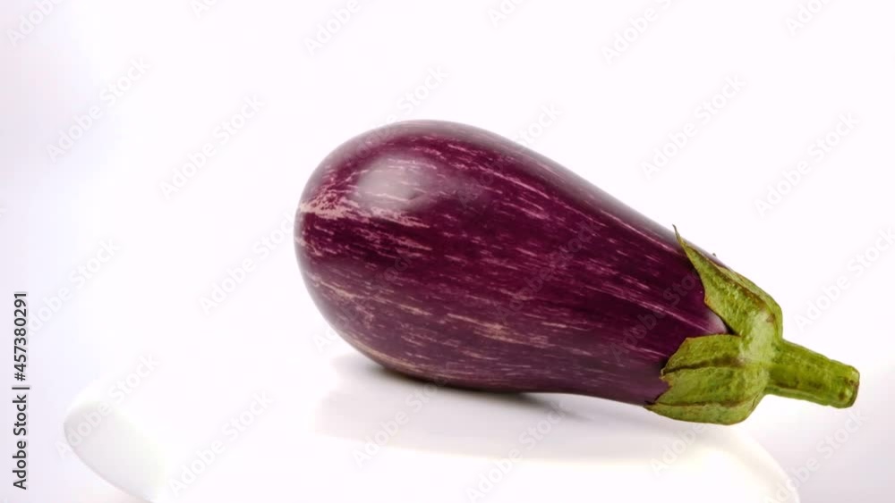 Purple eggplant with white stripes rotates on a white background. Ripe juicy organic eggplant cuts on a white background. Purple eggplant with white stripes rotates on a white background. Ripe juicy organic eggplant cuts on a white background.